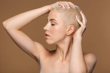 Çekici, kısa saçlı, kahverengi arkaplanda yalnız poz veren genç bir kadının güzel portresini kapat.