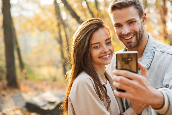 Gyönyörű Fiatal Szerelmesek Mobiltelefon Használata Közben Időt Töltenek Őszi Parkban — Stock Fotó