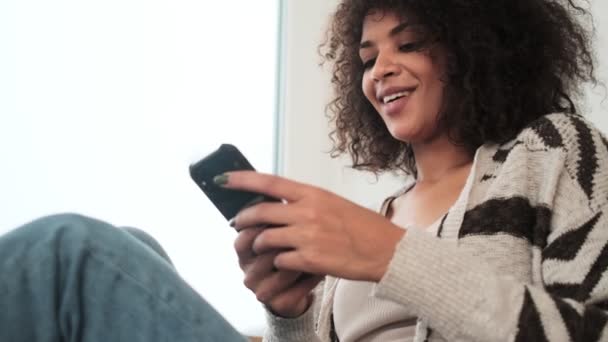 Young Amazing Beautiful African Curly Woman Indoors Home Using Mobile — Stock Video