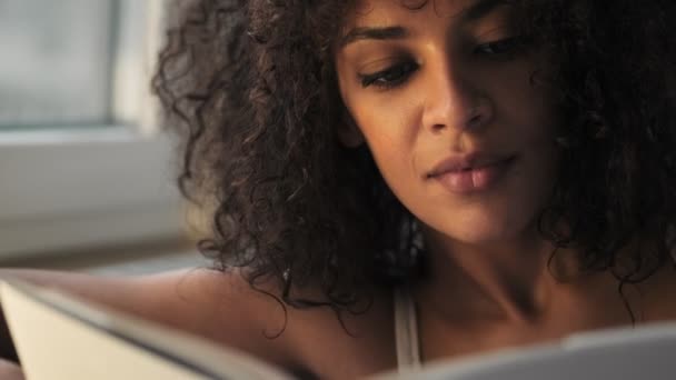 Young Concentrated Pretty African Curly Woman Indoors Home Reading Book — ストック動画