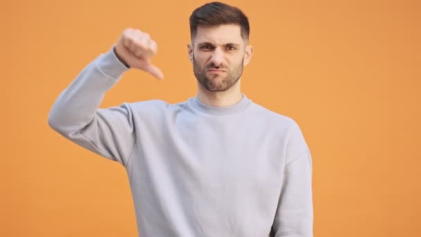 若い陰性の男が黄色の壁の背景に孤立し親指を下に示す — ストック動画