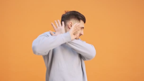 黄色の壁の背景に隔離された若い感情的な男は停止ジェスチャーを作る — ストック動画