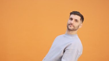 Genç, duygusal, pozitif bir adam sarı duvar arkasında dans ediyor.