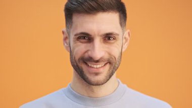 Sarı duvar arkasında izole edilmiş, gülümseyen duygusal genç adam.