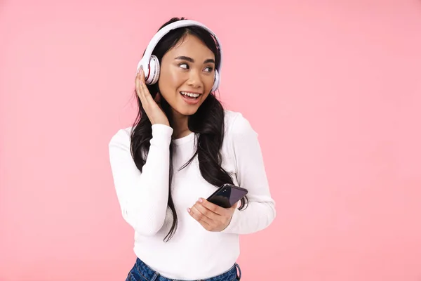 Веселая Красивая Молодая Азиатка Слушает Музыку Беспроводными Наушниками Изолированы Розовом — стоковое фото