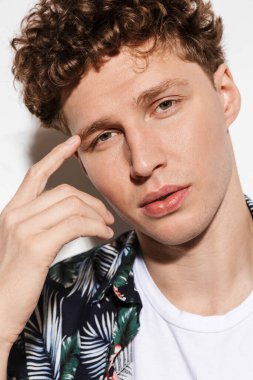 Beyaz arka planda izole edilmiş, poz veren ve kameraya bakan yakışıklı bir genç resmi.