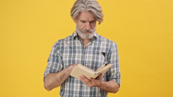 ハンサムな集中力のある男孤立した上に黄色の背景読書本手を振って誰か — ストック動画