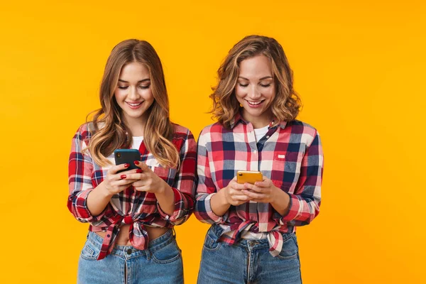 Изображение Двух Молодых Красивых Девушек Клетчатых Рубашках Улыбающихся Использующих Мобильные — стоковое фото