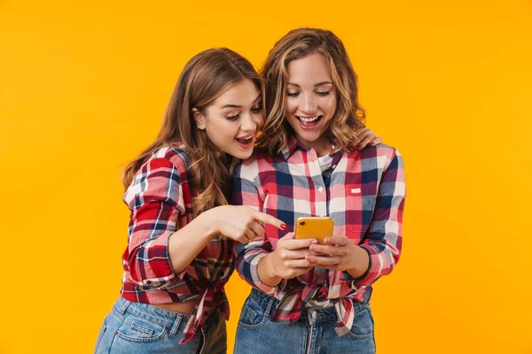 Изображение Двух Молодых Красивых Девушек Клетчатых Рубашках Улыбающихся Использующих Мобильный — стоковое фото