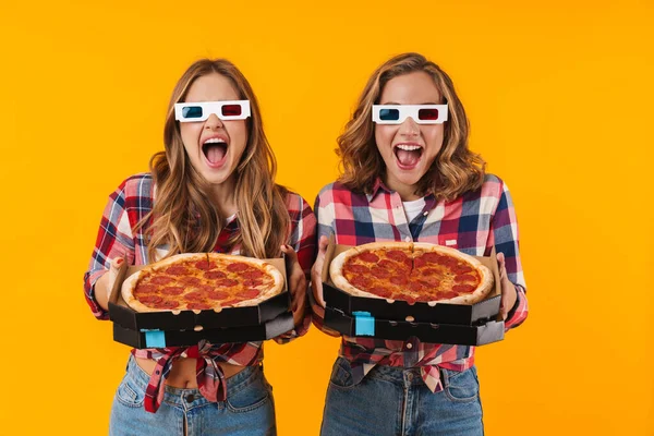 两个年轻漂亮的女孩戴着3D眼镜 手里拿着黄底上的披萨盒的照片 — 图库照片