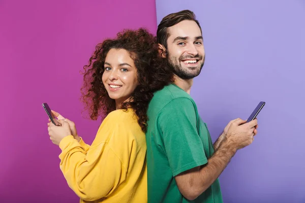 Retrato Casal Caucasiano Positivo Roupas Coloridas Sorrindo Segurando Celulares Volta — Fotografia de Stock