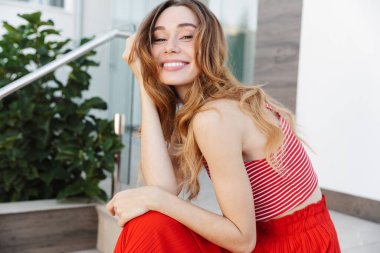 Açık havada otelin yakınlarında poz veren neşeli, güzel, genç bir kadının görüntüsü..