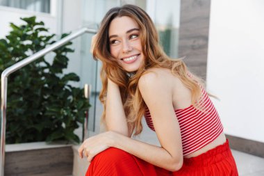 Otelin yakınlarında poz veren mutlu, pozitif, genç bir kadının fotoğrafı..