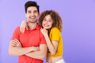 Neşeli beyaz kadın ve erkeğin portresi. Basit giyinmiş, gülümseyen ve kucaklaşan. Menekşe arka planda izole edilmiş.