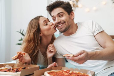 Çekici, mutlu bir çiftin evde yatıp pizza yediği görüntüsü.