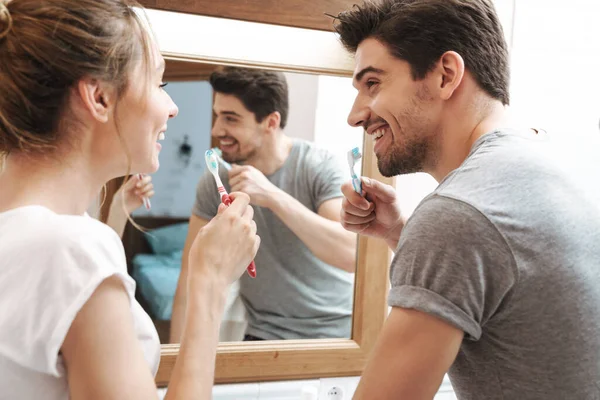 若いカップルの笑顔のイメージブラシや歯磨き粉とバスルームで歯をきれいにしながら — ストック写真