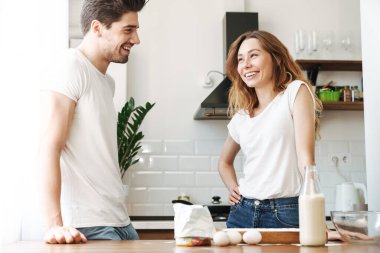 Mutlu, genç bir çiftin, evde süt ve yumurtalarla birlikte kahvaltı hazırlarken sevinç görüntüsü.