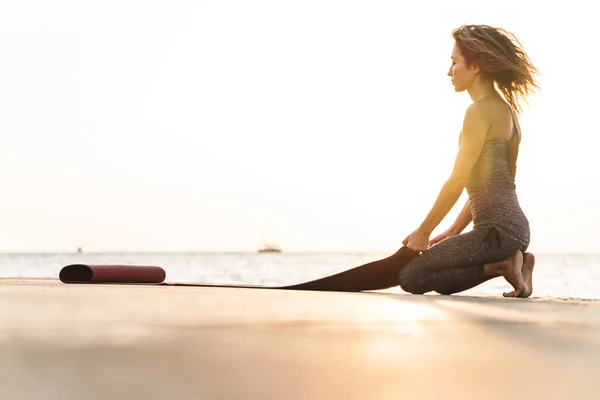 여성의 수트를 부두에 아침에 매트를 해변에 — 스톡 사진