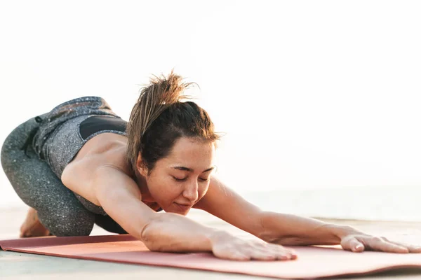 Eşofmanlı Kadın Sporcunun Sabah Sahilde Yoga Yaparken Vücudunu Mindere Gerdiği — Stok fotoğraf