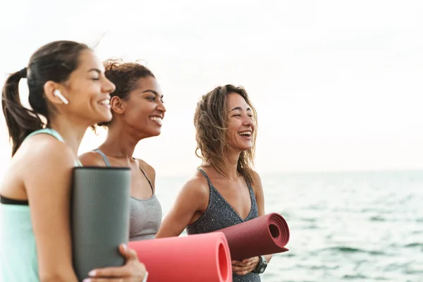 Tres Jóvenes Alegres Deportistas Caminando Por Playa Sosteniendo Colchonetas Fitness — Foto de Stock