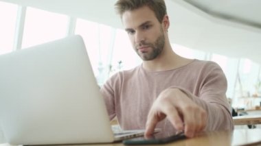 Memnun bir genç sakallı adam kafede otururken ve bilgisayarını içeride çalıştırırken telefonla konuşmaya başlıyor.