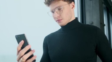 Ofiste cep telefonu kullanan yakışıklı, konsantre genç bir iş adamı.