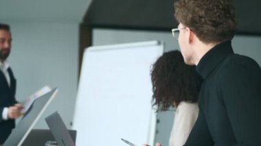 Ofisteki yakışıklı iş adamı meslektaşlarının önünde gemiye bir şeyler yazıyor.