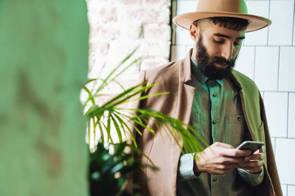 Attraente Giovane Uomo Barbuto Indossare Cappotto Utilizzando Telefono Cellulare Mentre — Foto Stock
