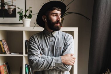 Ofiste dikilirken kablosuz kulaklık takan genç ve yakışıklı bir hippinin fotoğrafını çek.