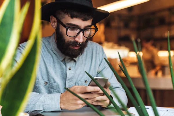 Photo Thinking Young Man Wearing Eyeglasses Using Cellphone While Sitting — Stock Photo, Image