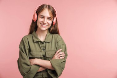 Kafkasyalı mutlu bir kadının pembe arka planda izole edilmiş kulaklık takıp gülümsemesi.