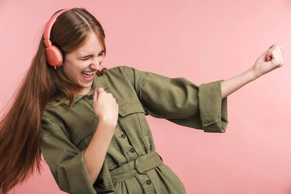照片中快乐的高加索女人使用耳机 在粉色背景下跳舞 — 图库照片