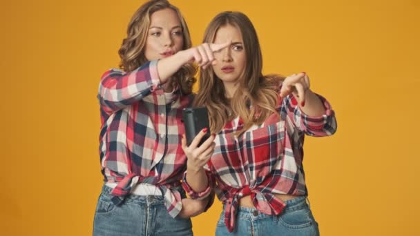 Jovens Meninas Concentradas Isoladas Sobre Fundo Parede Amarela Usando Telefone — Vídeo de Stock