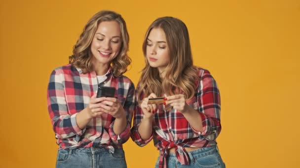 Jóvenes Niñas Concentradas Aisladas Sobre Fondo Amarillo Pared Utilizando Teléfono — Vídeos de Stock