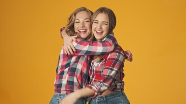 Unge Positive Jenter Venner Søstre Isolert Gul Vegg Bakgrunn Klemmer – stockvideo