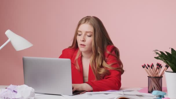 노트북 컴퓨터를 사용하여 작업하고 있습니다 그리고 분홍색 고립된 테이블에 머리를 — 비디오