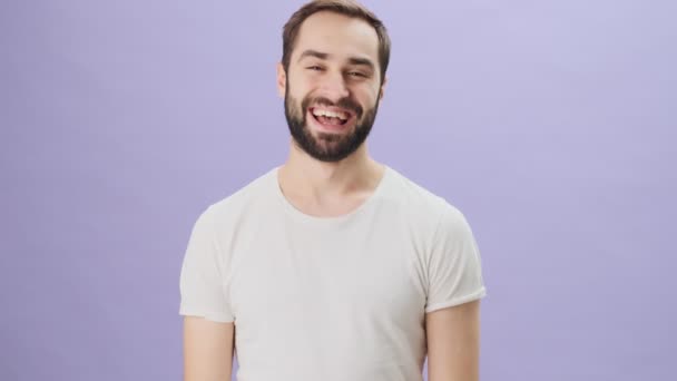 Ένας Χαμογελαστός Συναισθηματικός Νεαρός Που Φοράει Λευκό Μπλουζάκι Δείχνει Μια — Αρχείο Βίντεο