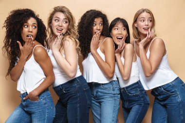 Mavi kotlu, çok uluslu genç kadınların şaşkınlıklarını bej arka planda izole edilmiş bir şekilde görüntüsü.
