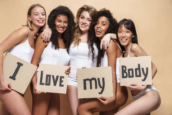 Beeld Van Vrolijke Multinationale Vrouwen Onderkleding Knuffelend Met Plakkaatjes Beige — Stockfoto