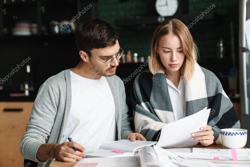 Image of happy young businesslike man and woman doing calculations and paperwork together in cafe