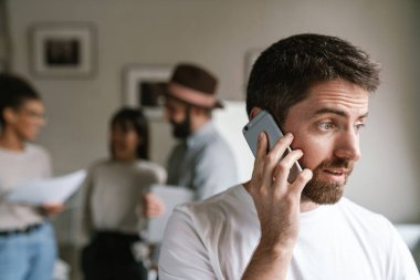 Ofiste birlikte çalışan çok ırklı genç iş adamlarının görüntüsü. Cep telefonu kullanan adam.