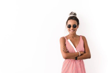 Neşeli, iyimser bir Afrikalı kadının beyaz duvar arkasına izole edilmiş, güneş gözlüğü takarak poz vermesi..