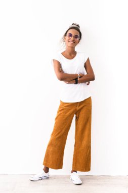 Beyaz duvar arka planında izole edilmiş korku pozları veren iyimser ve mutlu bir Afrikalı kadının görüntüsü..