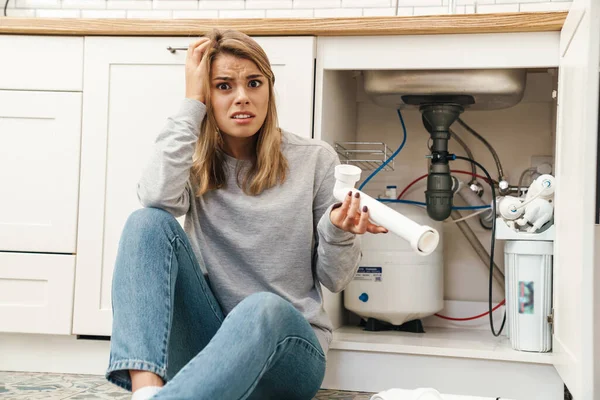 Photo Displeased Confused Blonde Woman Plumbing Pipes While Sitting Floor — Stock Photo, Image