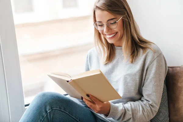 Foto Sorridente Bella Donna Occhiali Libro Lettura Mentre Seduto Vicino — Foto Stock