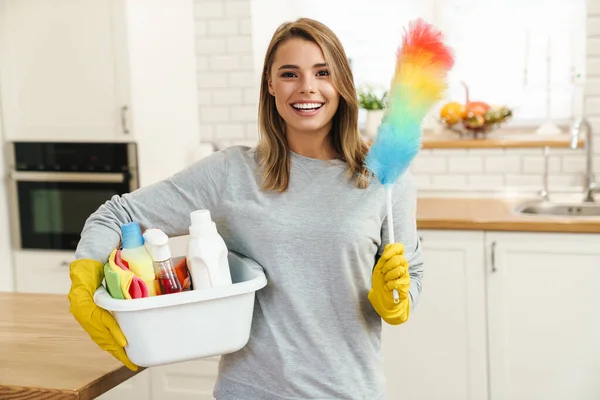 Foto Sonriente Joven Ama Casa Con Guantes Sosteniendo Botellas Limpiador — Foto de Stock