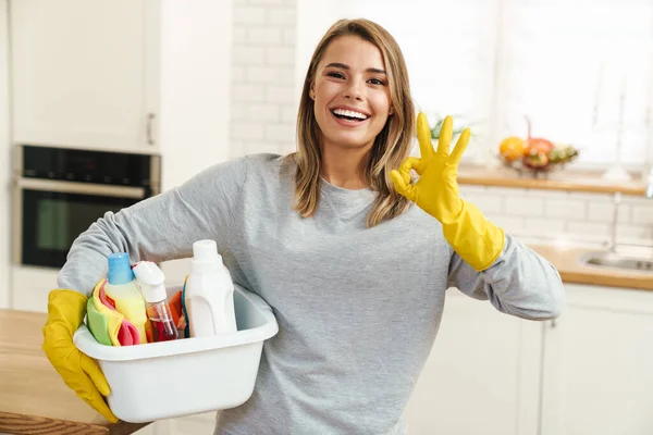 Foto Leende Ung Kvinna Hemmafru Handskar Som Håller Rengöringsmedel Flaskor — Stockfoto