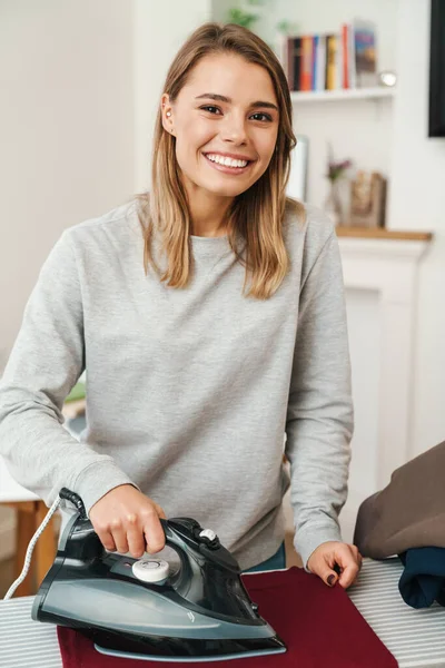 Photo Cheerful Young Beautiful Woman Housewife Smiling While Ironing Clothes — Stock Photo, Image