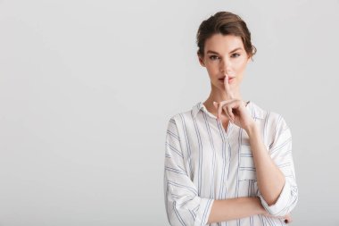 Beyaz arka planda izole edilmiş kamerada sessizlik jesti yapan ciddi bir kadın görüntüsü