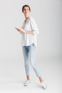 Beyaz arka planda izole edilmiş gülümseyen ve cep telefonu kullanan neşeli güzel bir kadın görüntüsü